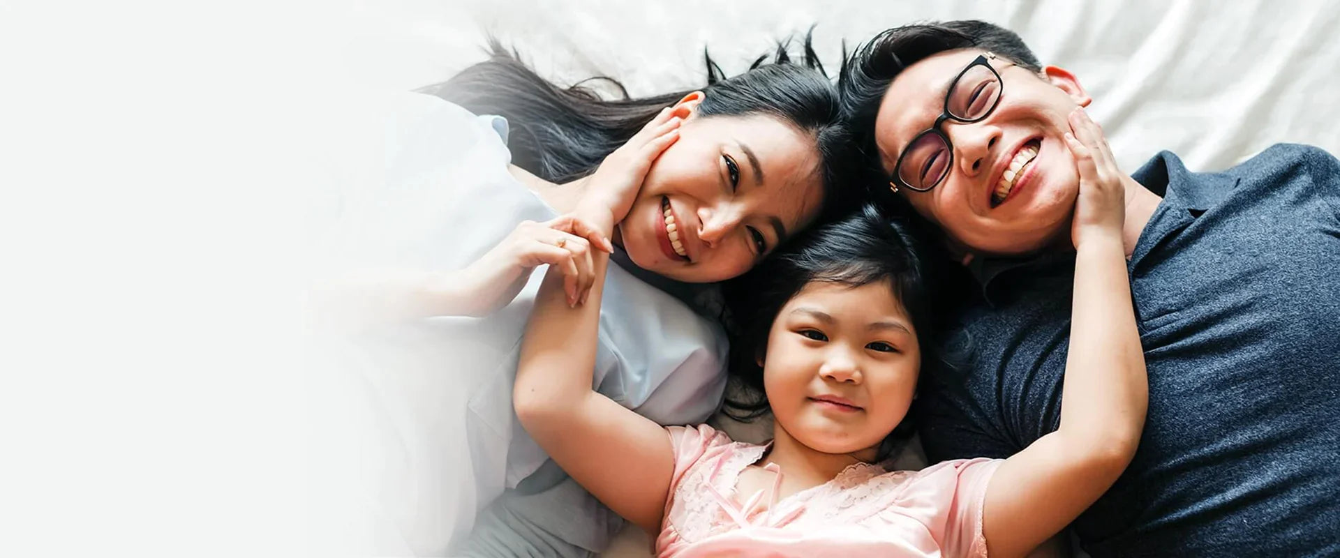 family laying on bed looking up at camera