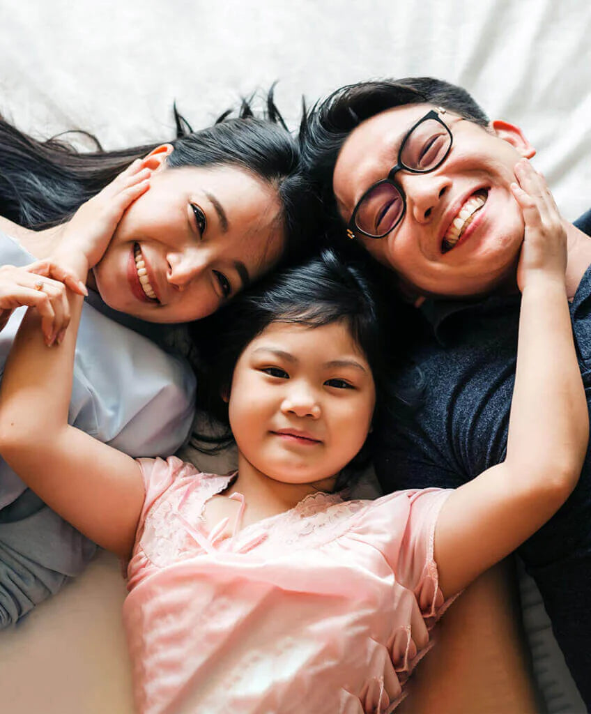 family laying on bed looking up at camera